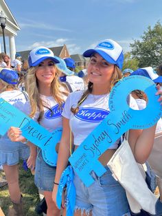 two beautiful young women holding blue signs in front of a building