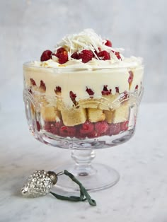 a trifle with raspberries and whipped cream in a glass dish on a marble table