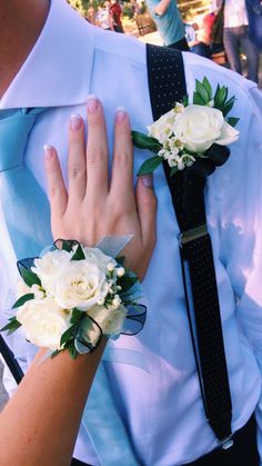 two people wearing ties and flowers on their hands, one is holding the other's hand