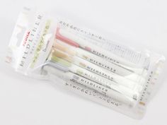 four different colored pencils in a plastic bag on a white surface with japanese writing