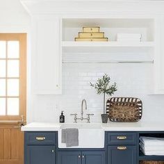 a kitchen with blue cabinets and white counter tops is pictured in this image, there are baskets on the sink