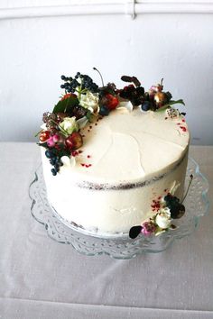 a cake with white frosting and colorful flowers on the top is sitting on a glass platter