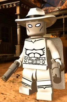 a lego man in a white hat and costume holding a large metal object while standing on a dirt ground