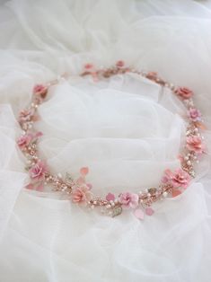 a necklace with pink flowers and pearls on top of white tulle skirted fabric