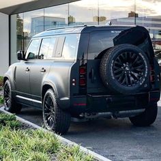 an suv parked in front of a building with its door open and the rear tire missing