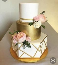 a white and gold wedding cake with pink flowers