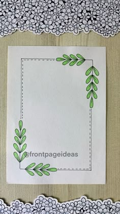 a piece of paper with green leaves on it next to some doily and lace