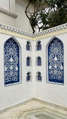 an intricately designed wall with blue and white tiles on the outside, in front of a tree