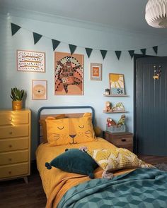 a child's bedroom with blue walls, yellow bedding and pictures on the wall