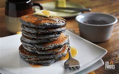 a stack of pancakes on a plate with butter and syrup