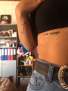 a woman with a small tattoo on her stomach saying i am enough in black ink