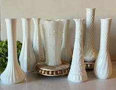 several white vases are lined up on a table