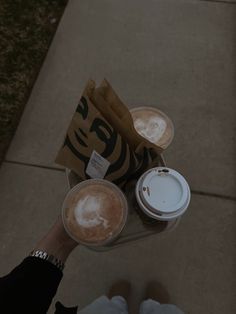 two cups of coffee are sitting on the sidewalk