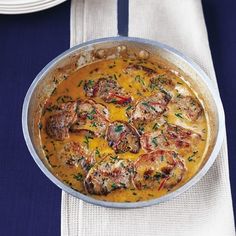 a pan filled with food sitting on top of a blue table cloth next to plates