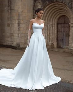 a woman in a white wedding dress standing outside