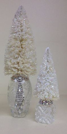 three small white trees in a clear glass vase with crystal accents on the top and bottom