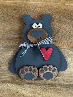 a wooden bear with a heart and paw print on it's chest sitting on a wood floor