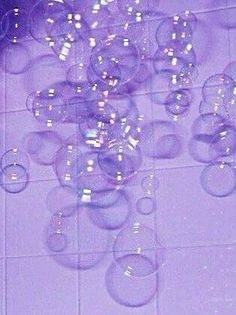 a bunch of bubbles floating in the air on a tiled floor next to a wall