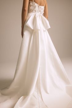 a woman in a white wedding dress with a large bow on the back of it