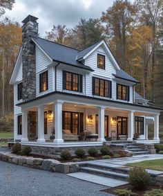 a white house with black shutters on the front porch and stairs leading up to it