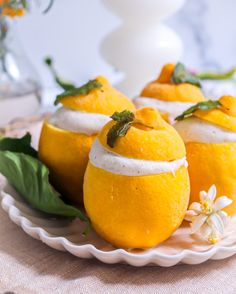 three oranges with whipped cream on them are sitting on a plate next to flowers