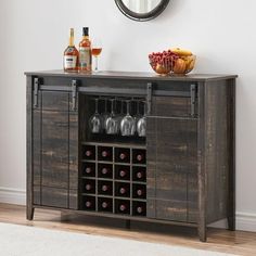 a wooden cabinet with wine glasses and bottles on it next to a wall mounted mirror