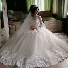 a woman in a white wedding dress sitting on a wooden floor next to a bed