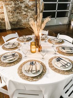 a table set with plates and silverware for two people to eat at, in front of a brick wall