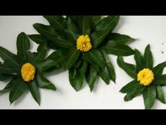 three green leaves with yellow flowers on them