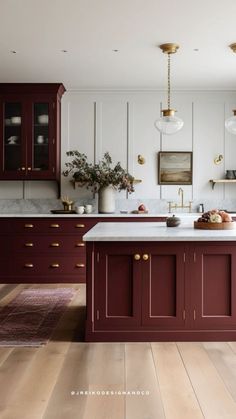 a kitchen with red cabinets and white counter tops, gold pulls on the cabinet doors