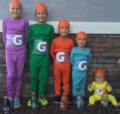 five children wearing costumes standing in front of a brick wall with their hands on their hipss