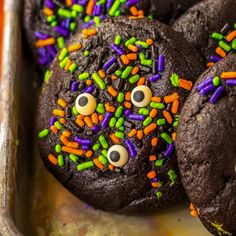 chocolate cookies decorated with sprinkles and googly eyes are on a tray