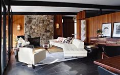 a living room filled with furniture next to a stone wall covered in wood paneling