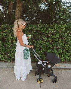 a woman in a white dress is pushing a stroller