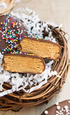 two pieces of cake sitting on top of a basket next to cookies and sprinkles