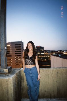 a woman standing on top of a building next to a tall pole with buildings in the background