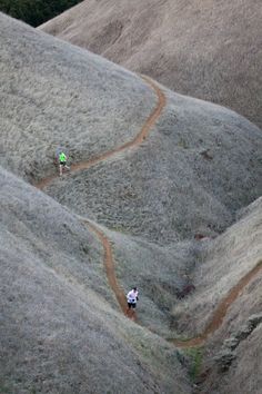 two people hiking up a hill in the mountains