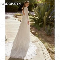 a woman in a wedding dress standing on a sidewalk next to cacti and succulents