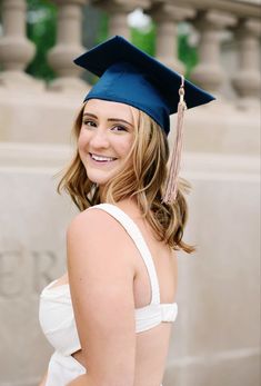 a woman wearing a graduation cap and gown in front of a building with columns on either side