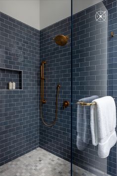 a bathroom with blue tiled walls and gold shower faucet next to the bathtub