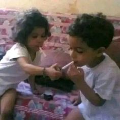 two children sitting on a bed brushing their teeth