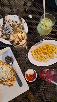 a table topped with plates of food next to glasses of juice and sauces on top of it