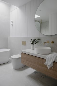 a bathroom with a sink, toilet and bathtub next to a round mirror on the wall