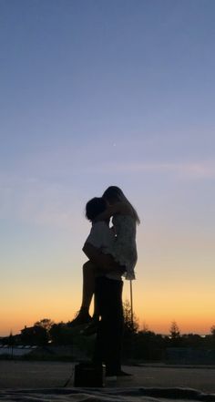 a man and woman kissing in front of the sun