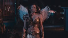 a woman dressed in costume standing outside at night with wings spread around her body and chest