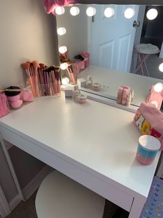 a white vanity with lights and makeup products on it