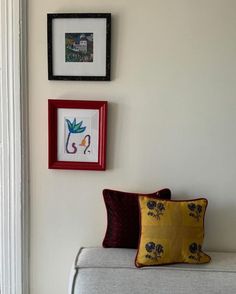 two framed pictures hang on the wall next to a couch with pillows and throw pillows