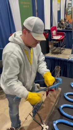 a man in yellow gloves is working on some blue objects at a table with other people