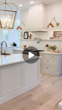 a large kitchen with white cabinets and an island in the middle, surrounded by hanging lights