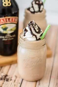 two glasses filled with ice cream and whipped cream next to a bottle of bailey's